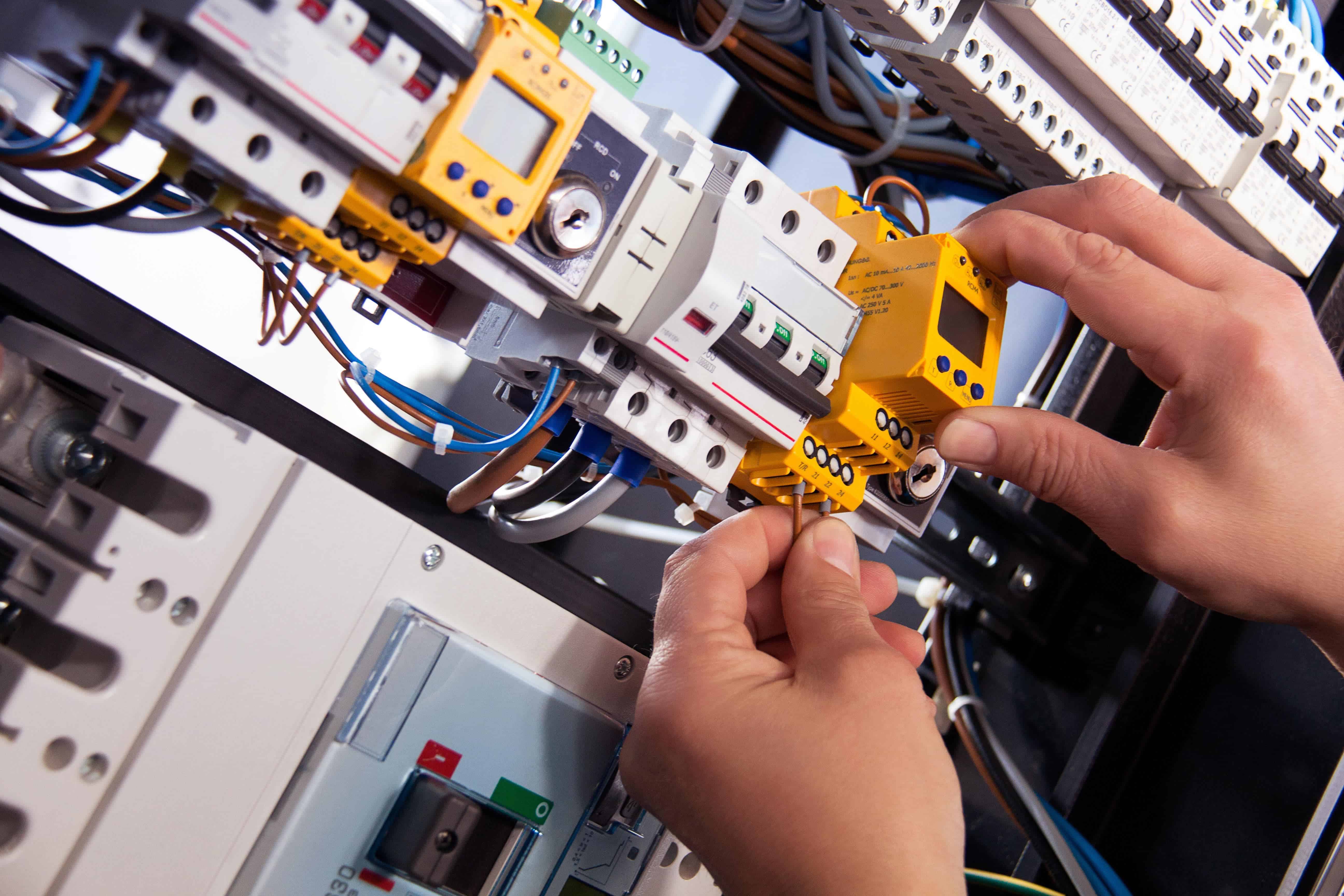 Picture of hands placing an electrical component on to a rack in a control panel
